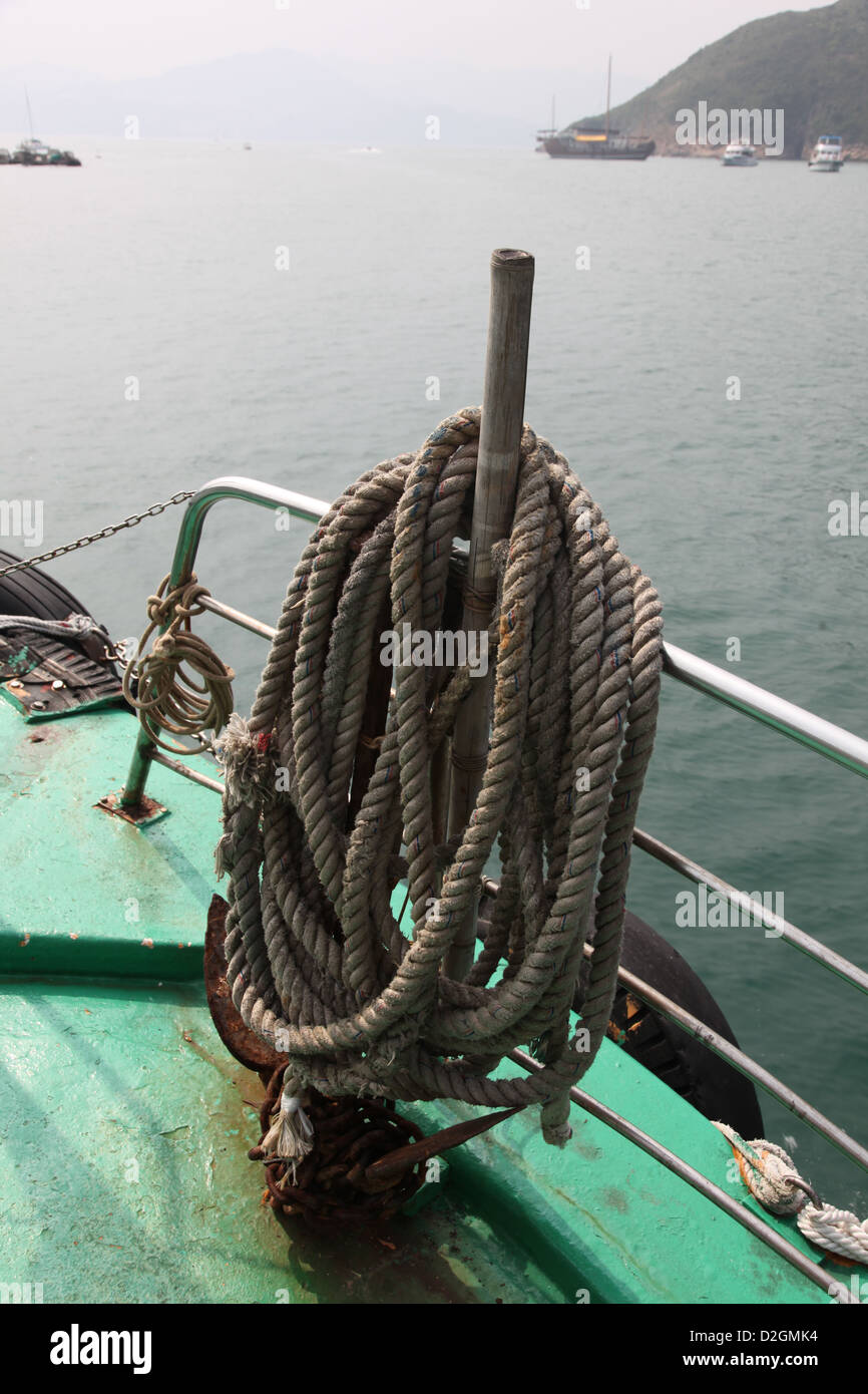 Si tratta di una foto di una lunga corda che viene arrotolato intorno a un bastone di legno in una barca sul mare Foto Stock