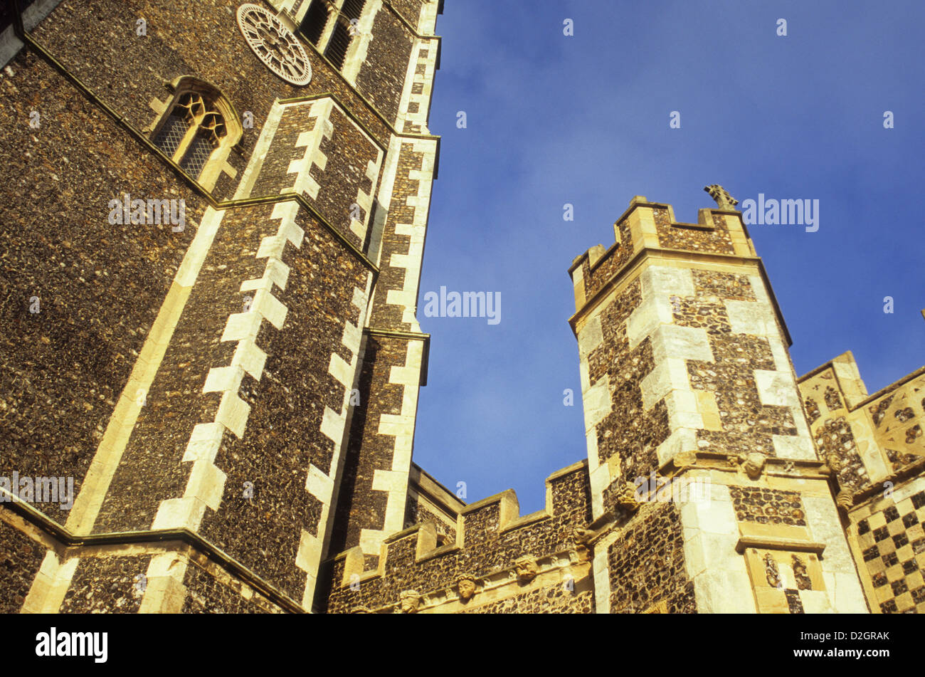 Dettaglio del flinstone xv secolo gotico perpendicolare torri della chiesa nella luce calda sotto il cielo blu Foto Stock