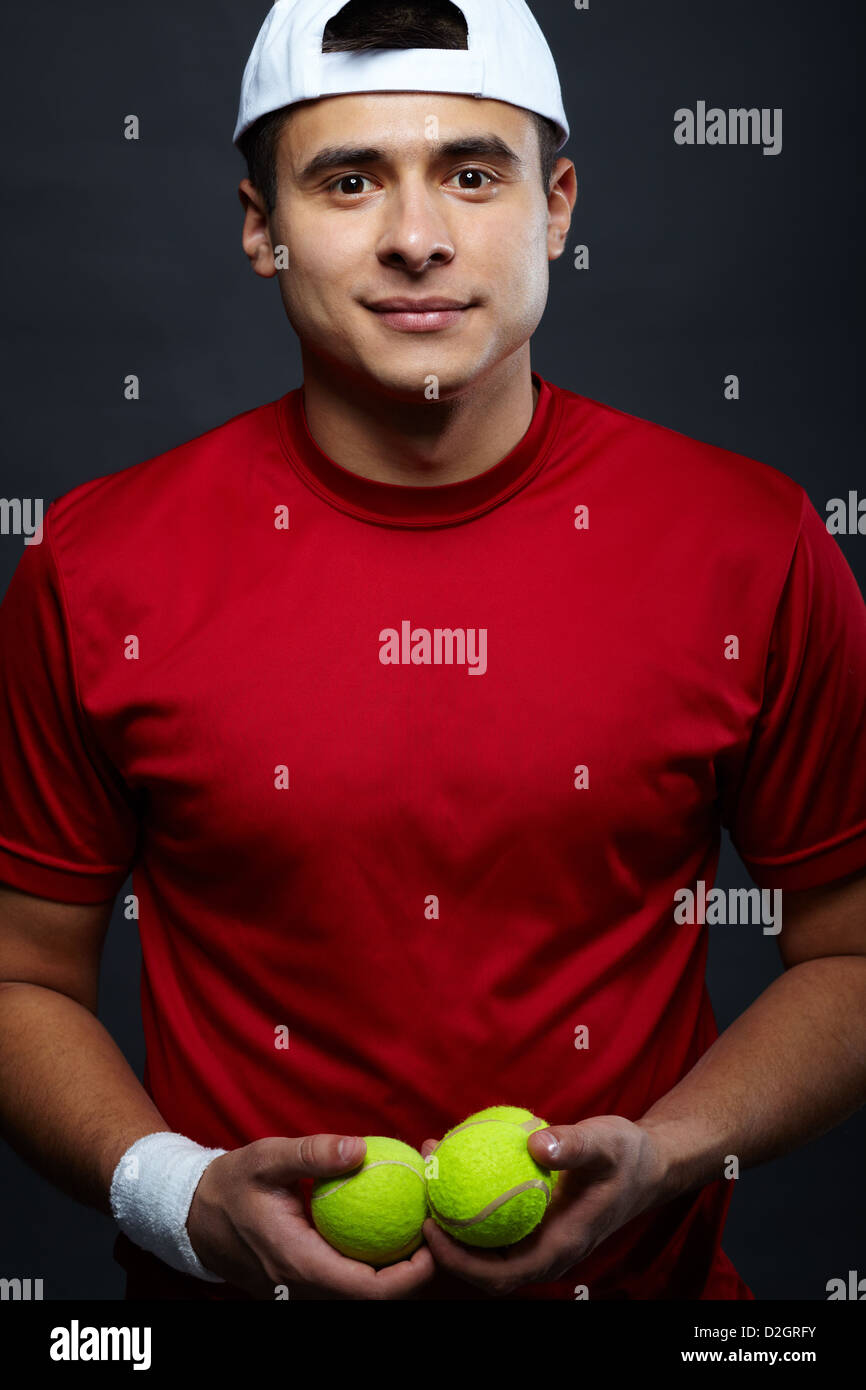 Ritratto di Allegro ragazzo in azienda di abbigliamento sportivo di palle da tennis e guardando la fotocamera Foto Stock