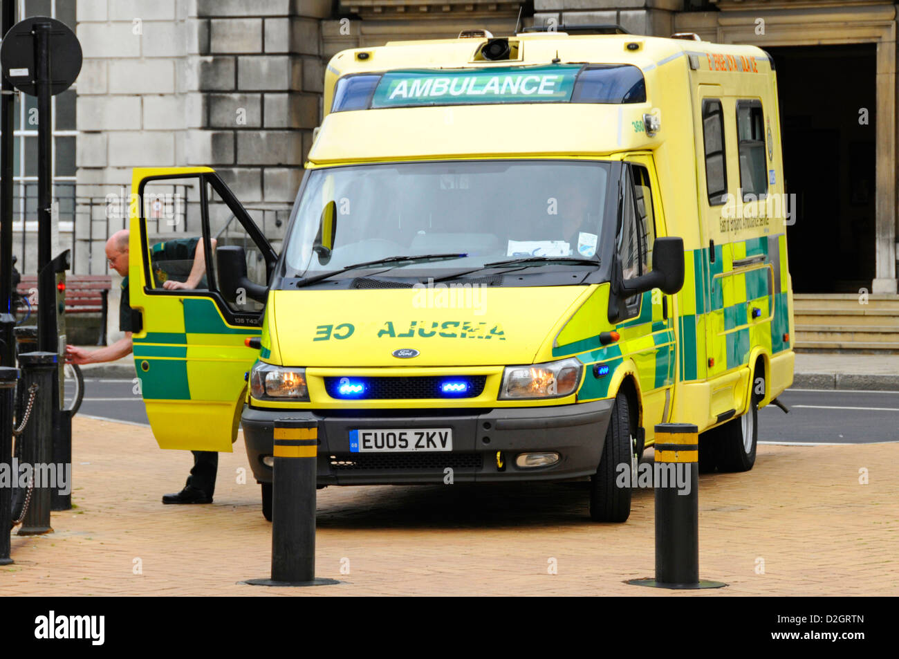 Autista di ambulanza sulla chiamata di emergenza cercando di spingere i pulsanti per accedere a Chelmsford area pedonale per lo shopping di alta al di là della strada in salita e discesa paracarri Foto Stock