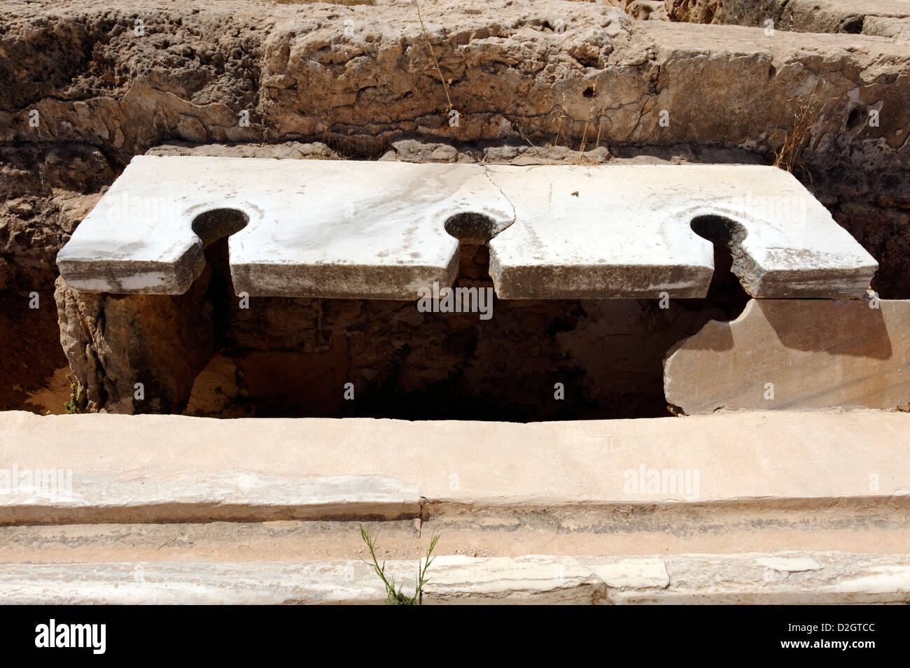 Leptis Magna. La Libia. Vista ravvicinata di marmo posti a sedere alla più grande delle due suite di latrine presso le Terme di Adriano Foto Stock