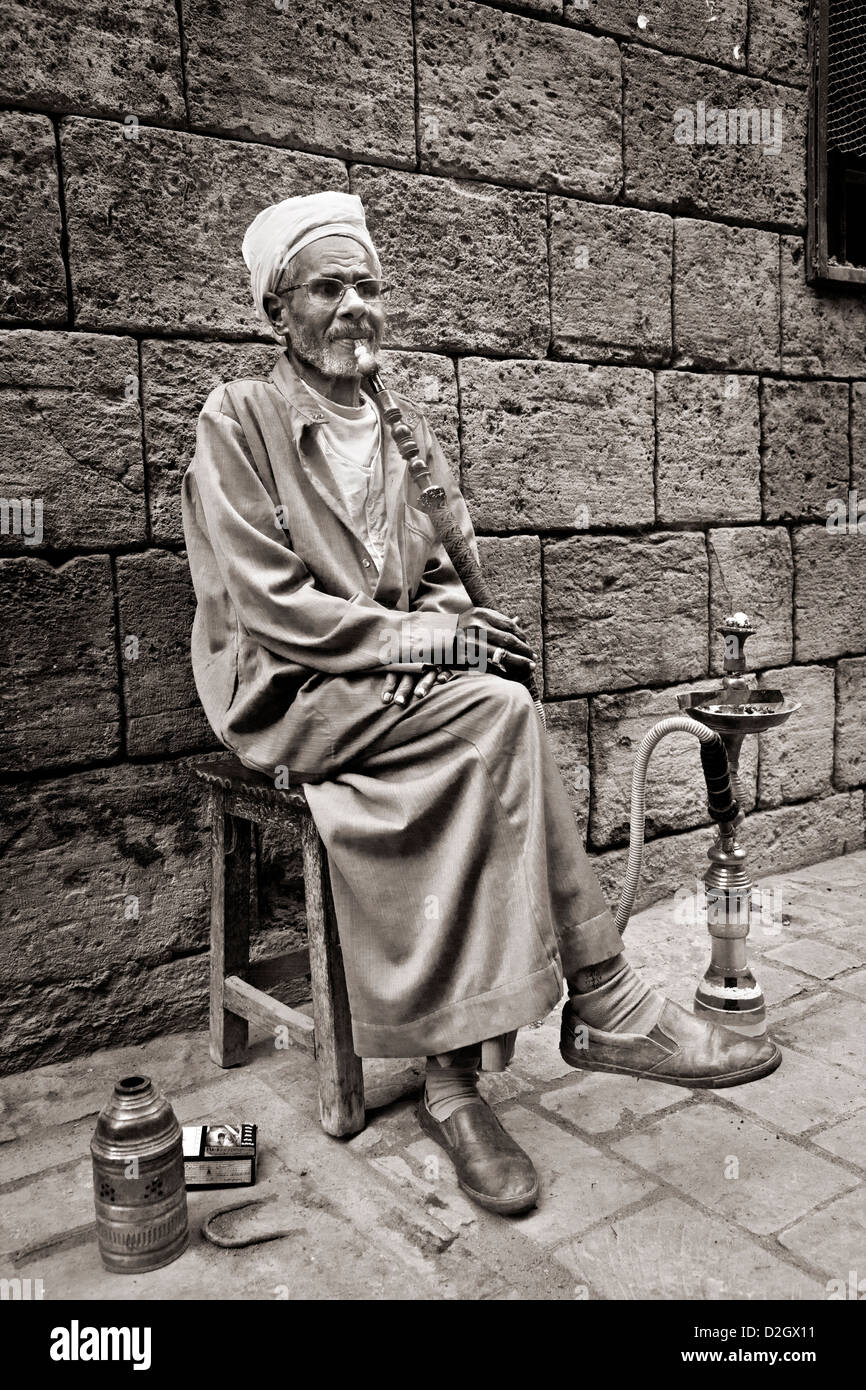 Un vecchio uomo fuma sheesha in Khan el-Khalili bazaar del Cairo, Egitto. Versione a colori disponibili in D2TJAN Foto Stock