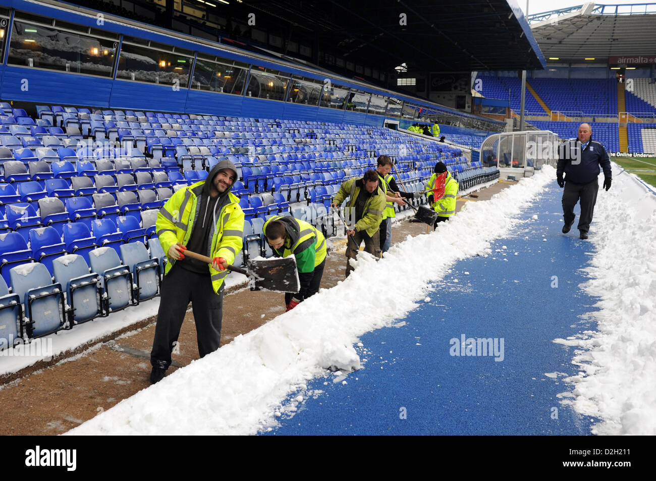 Il personale lavora duro per eliminare la neve e il ghiaccio da Birmingham City Football Ground folla stand Foto Stock