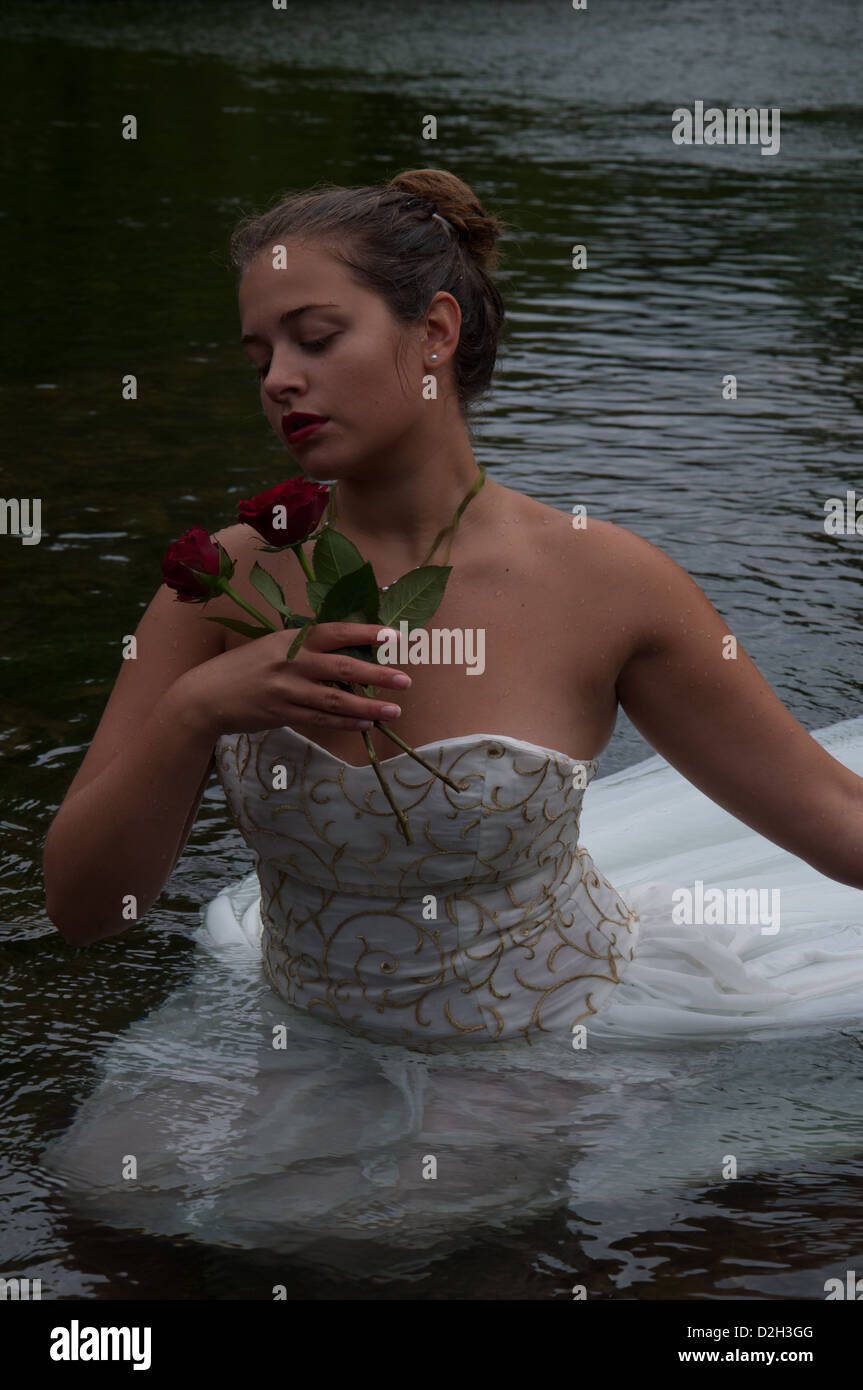 Signora giovane in un fiume indossando un bianco abito da sposa Foto Stock