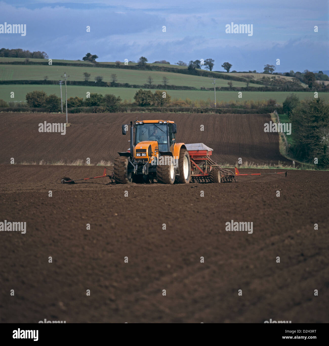 Renault trattore con un pneumatico Ferrag seminatrice piantando un autunno di raccolto di cereali in ammenda seedbed in East Devon, Novembre Foto Stock