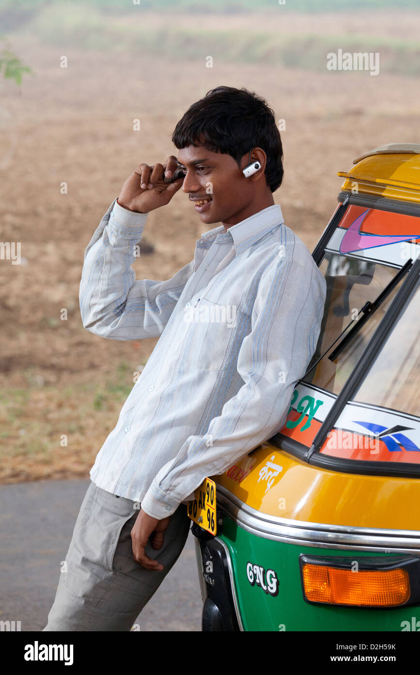 India, Uttar Pradesh, rickshaw driver utilizzando il telefono cellulare con un auricolare bluetooth Foto Stock