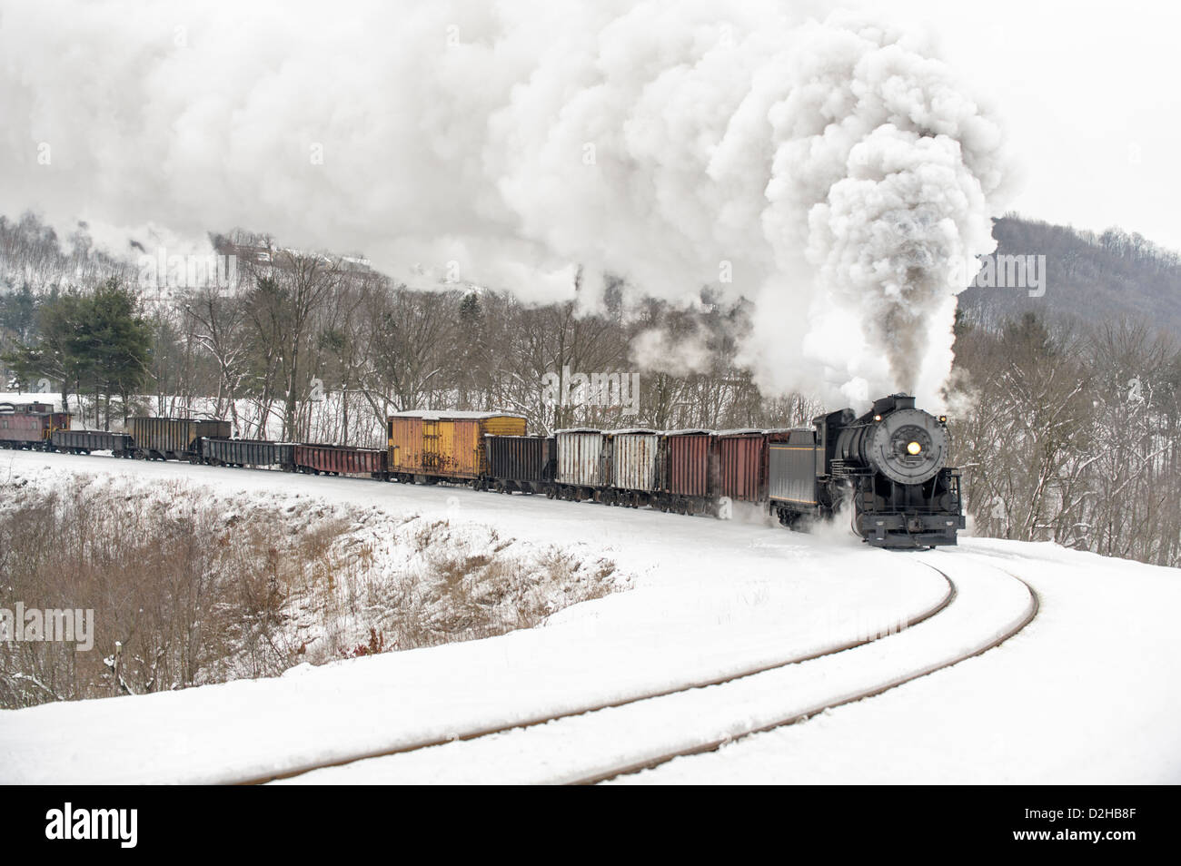 Locomotiva a vapore e treno frieght curva di arrotondamento in inverno la neve con un grande ed alto pennacchio di fumo, Cumberland, MD, Maryland, Stati Uniti d'America. Foto Stock