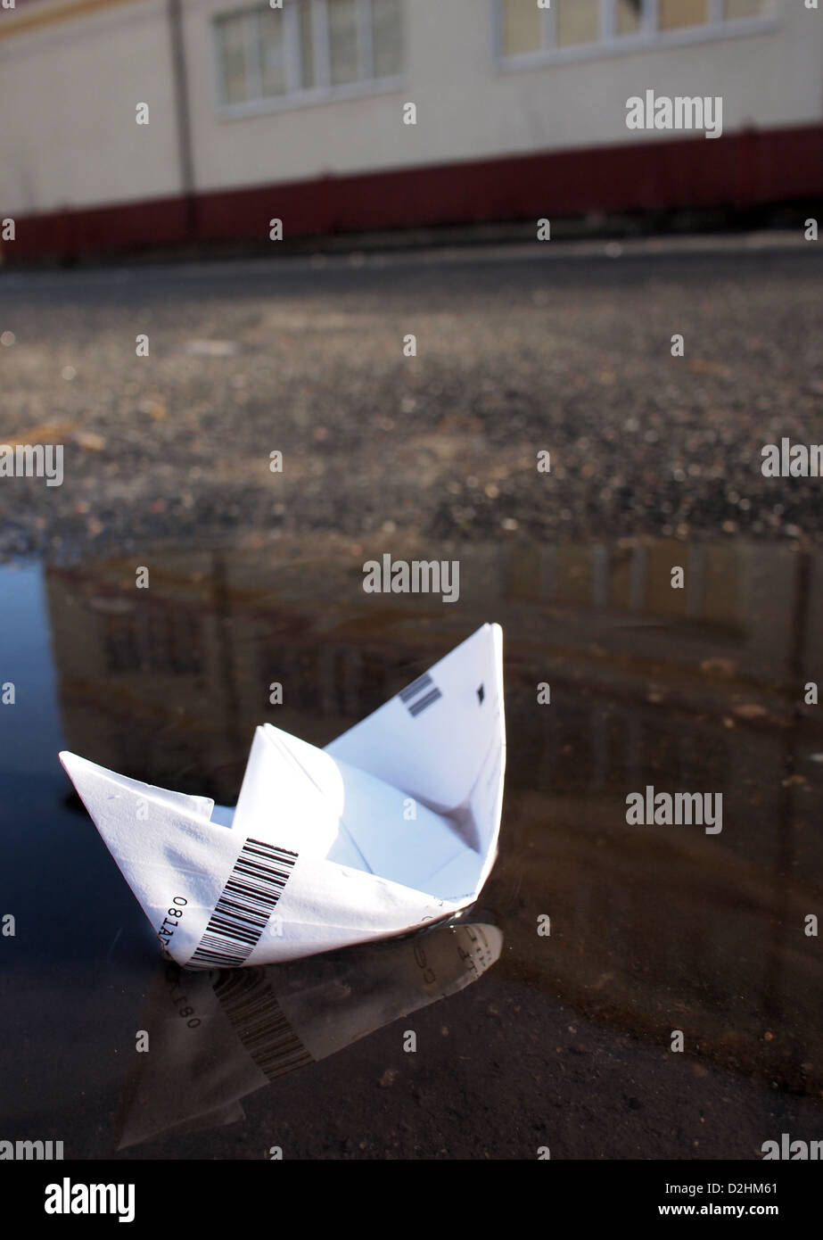 Barca di carta in una pozza di fronte a casa Foto Stock