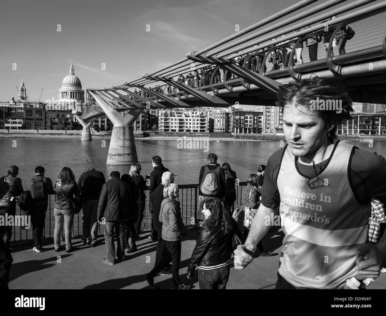 Un giovane uomo che corre sotto il Millenium Bridge in una giornata di sole Foto Stock