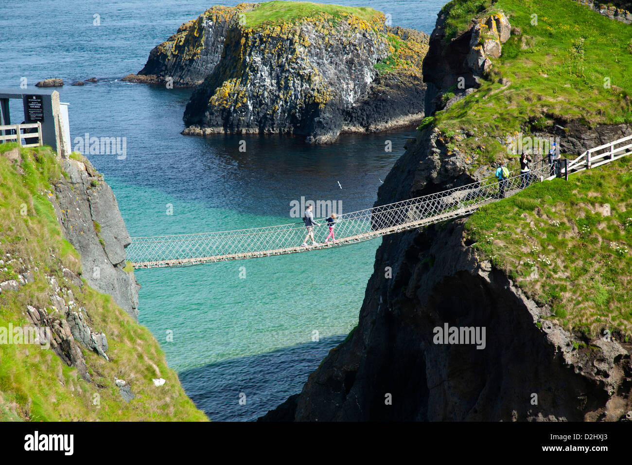 Le persone che attraversano le Carrick-a-Rede ponte di corde, County Antrim, Irlanda del Nord. Foto Stock