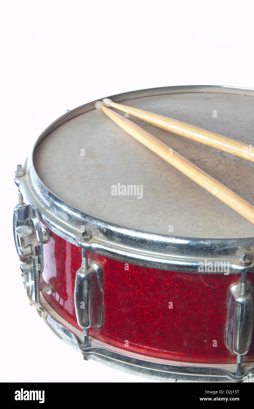 Un rosso snare drum è fotografato nel profilo con bacchette su uno sfondo bianco. Vi è abbondanza di spazio copia disponibile. Foto Stock