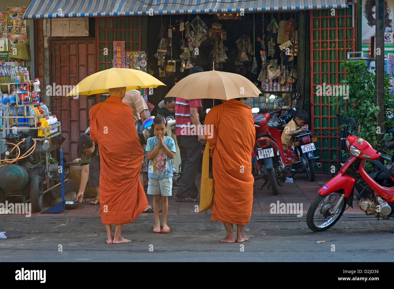 Phnom Penh, Cambogia, una ragazza pregando davanti dei monaci buddisti Foto Stock