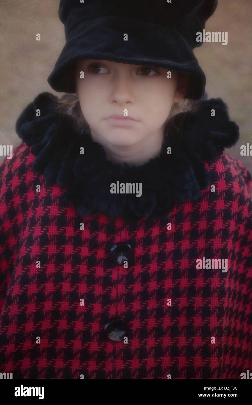 Una ragazza triste con un mantello rosso e un cappello nero Foto Stock