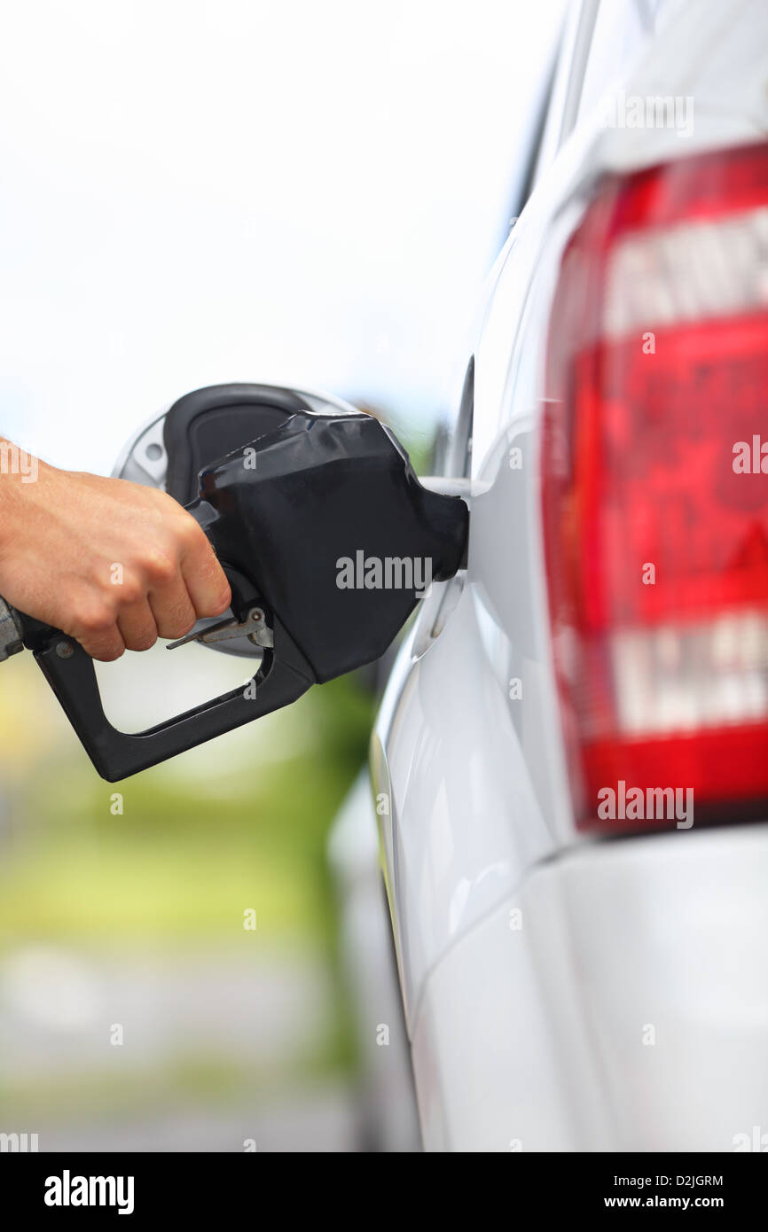 Closeup dell uomo di riempimento carburante benzina in auto ugello di tenuta. Foto Stock