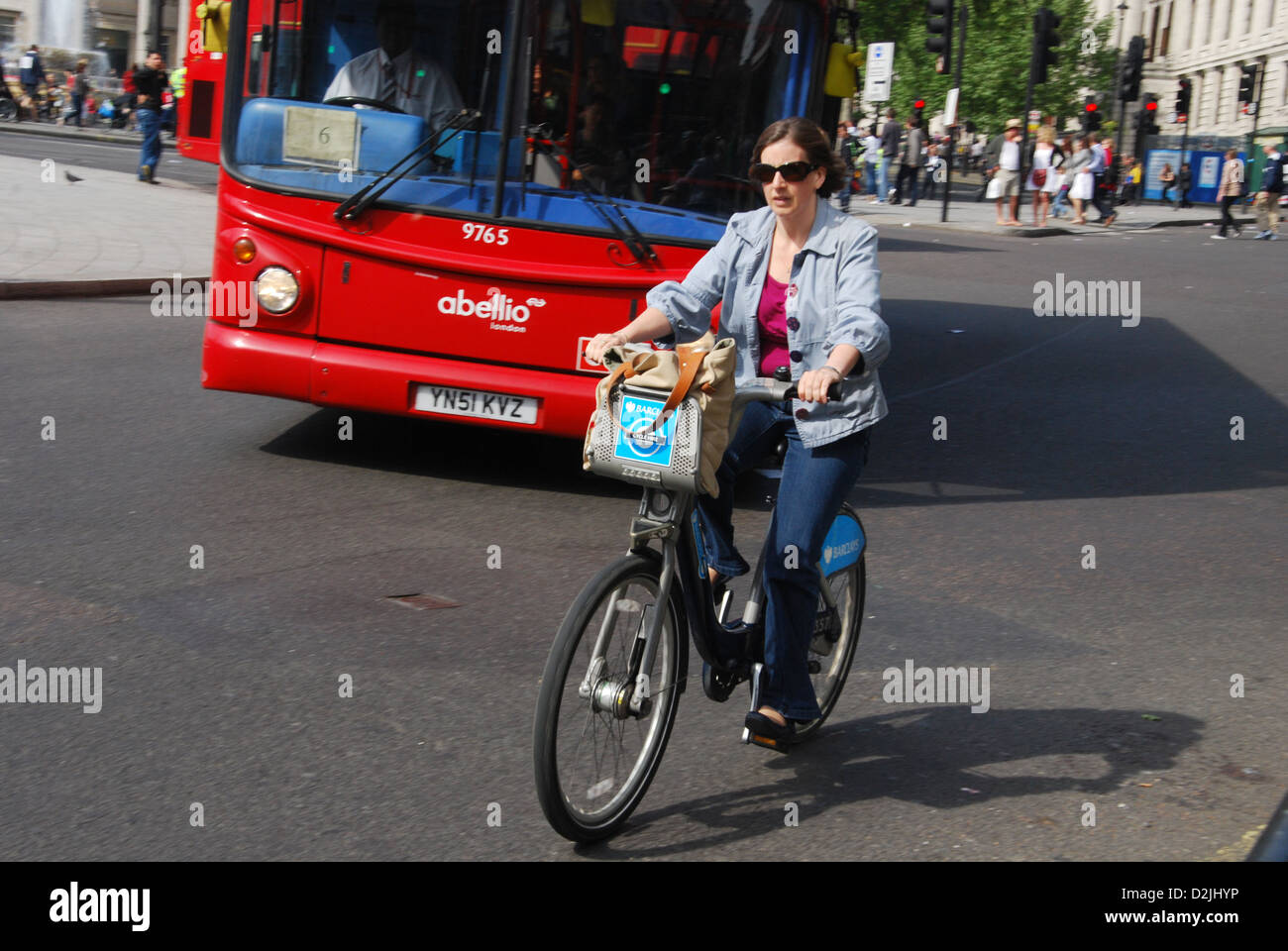 Donna in bicicletta tra le vetture, Trafalgar Square London Regno Unito Foto Stock