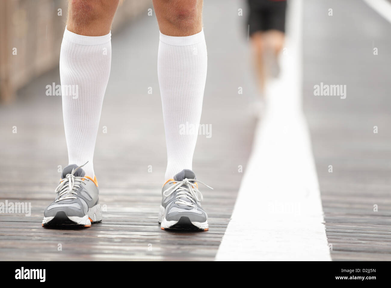 Scarpe Running closeup e calze di compressione sulla guida del maschio. Primo piano della runner piedi sul ponte di Brooklyn, New York City Foto Stock