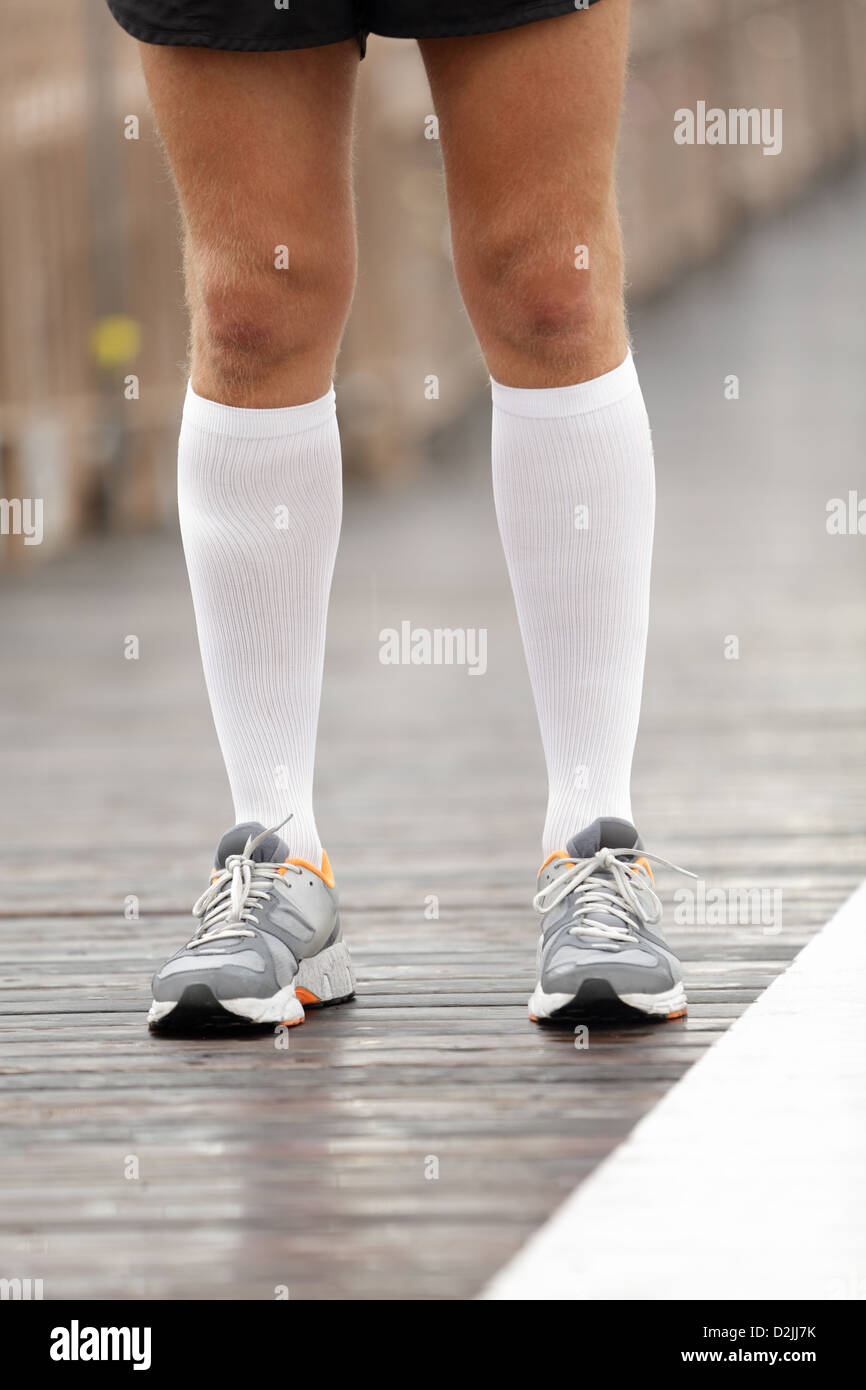 Running scarpe e calze di compressione sulla guida del maschio. Primo piano della runner piedi sul ponte di Brooklyn, New York City Foto Stock