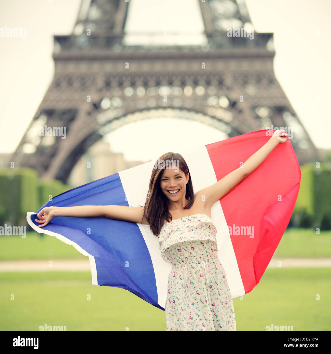 Donna che mantiene bandiera francese dalla Torre Eiffel a Parigi. Turisti in viaggio in Europa. Foto Stock