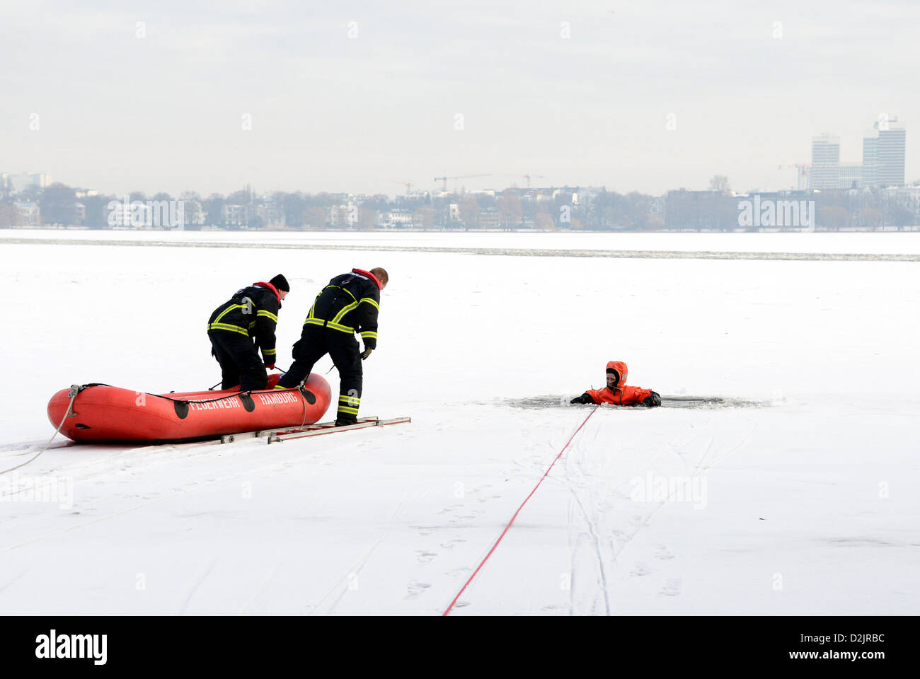 Vigili del fuoco condurre un trapano in cui il salvataggio di una donna che ha rotto attraverso il ghiaccio dell'Alster Amburgo, Germania, 25 gennaio 2013. Il dipartimento dei vigili del fuoco ha tenuto una presentazione di salvataggio di ghiaccio e abbiamo parlato circa i pericoli di entrare in ghiaccio sottile su laghi e fiumi. Foto: Daniel Bockwoldt Foto Stock