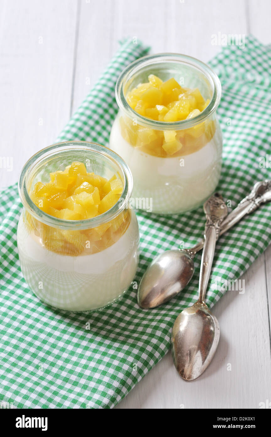 Dessert di frutta con mango in vasetti di vetro bianco su sfondo di legno Foto Stock