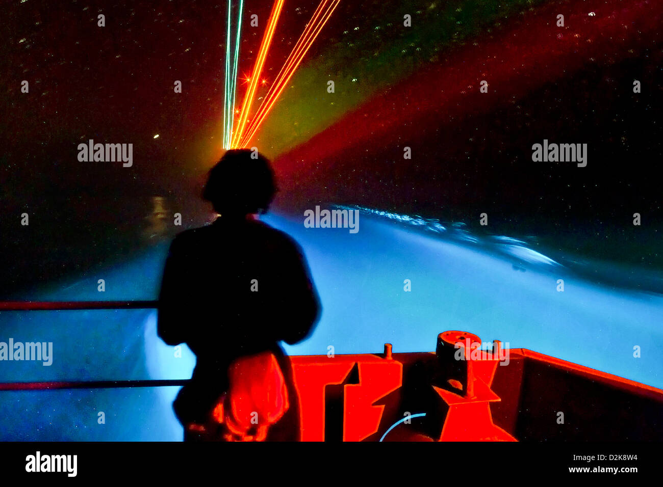Un marinaio sorge guarda sul fiocco della portaerei USS Carl Vinson come organismi di bioluminescenza e su aeromobili approccio finale la luce la notte intorno a lei il 2 febbraio 2011 in mare Arabico. Foto Stock