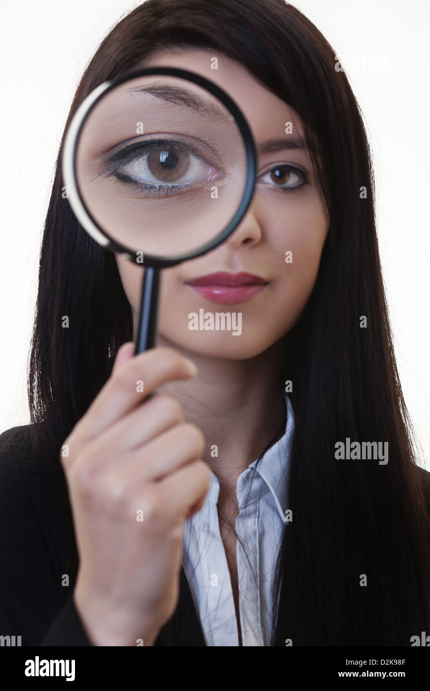 Donna che mantiene una lente di ingrandimento sopra il suo occhio Foto Stock