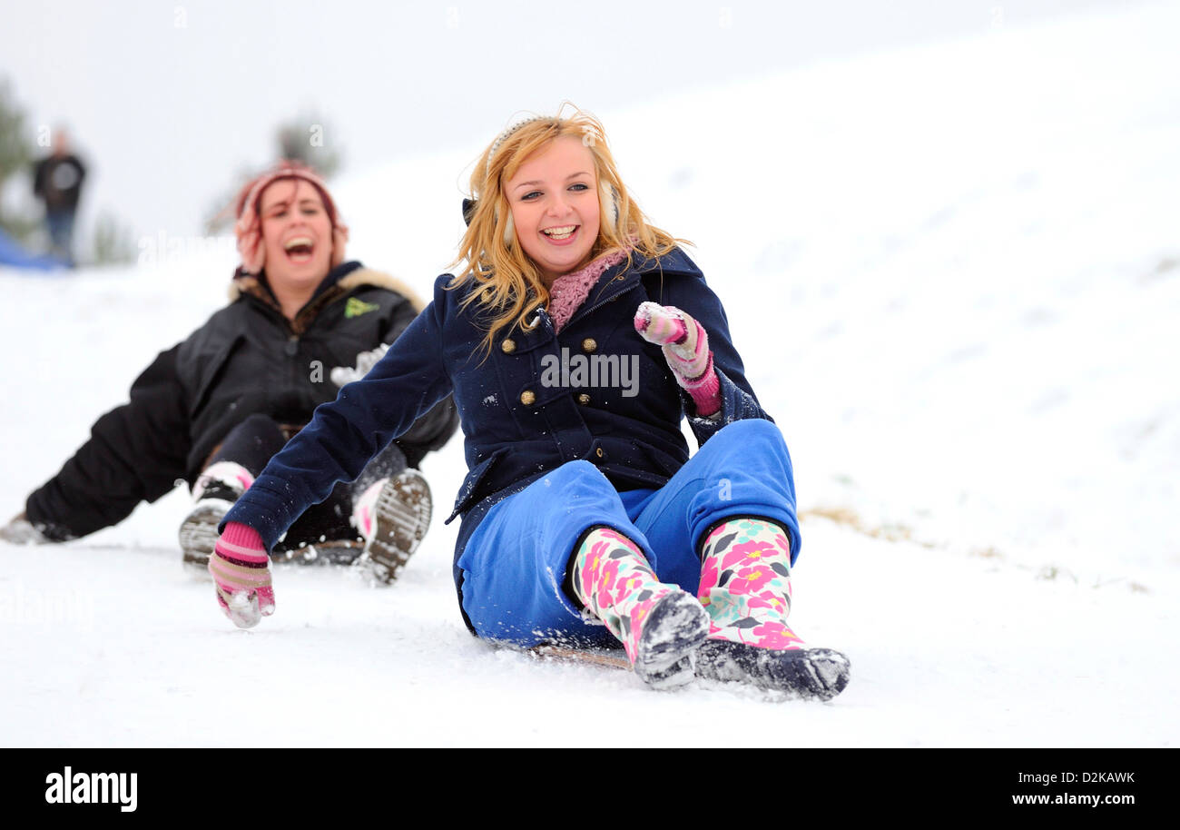 Due giovani donne godendo lo slittino insieme verso il basso una coperta di neve collina su un inverni freddi giorno. Foto Stock