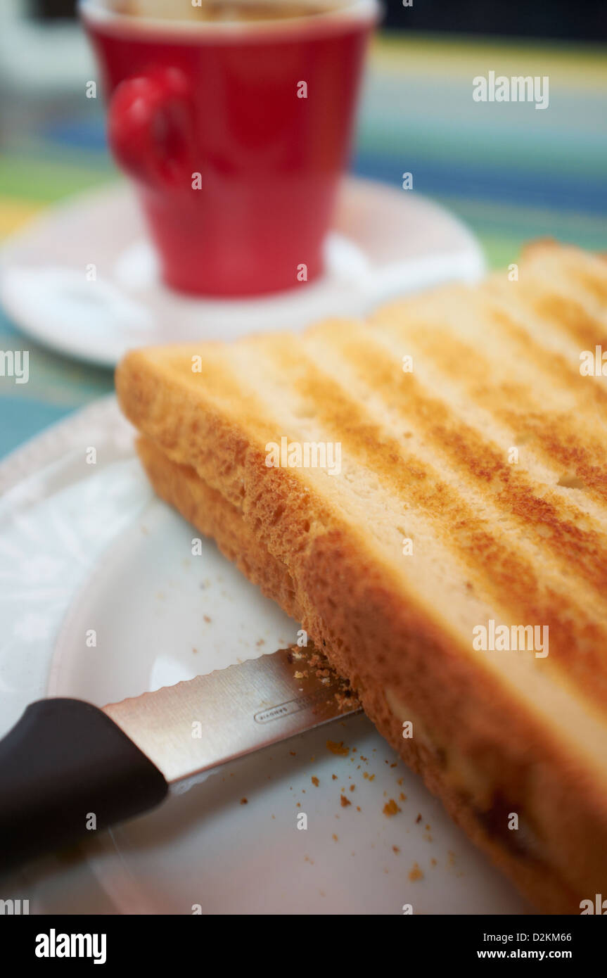 Appena sfornati toastie con red tazza da caffè in backgroundFreshly realizzato toastie con red tazza da caffè in background Foto Stock