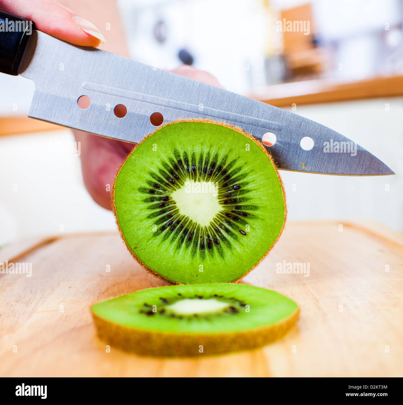 Donna taglio mani fresche Kiwi in cucina Foto Stock