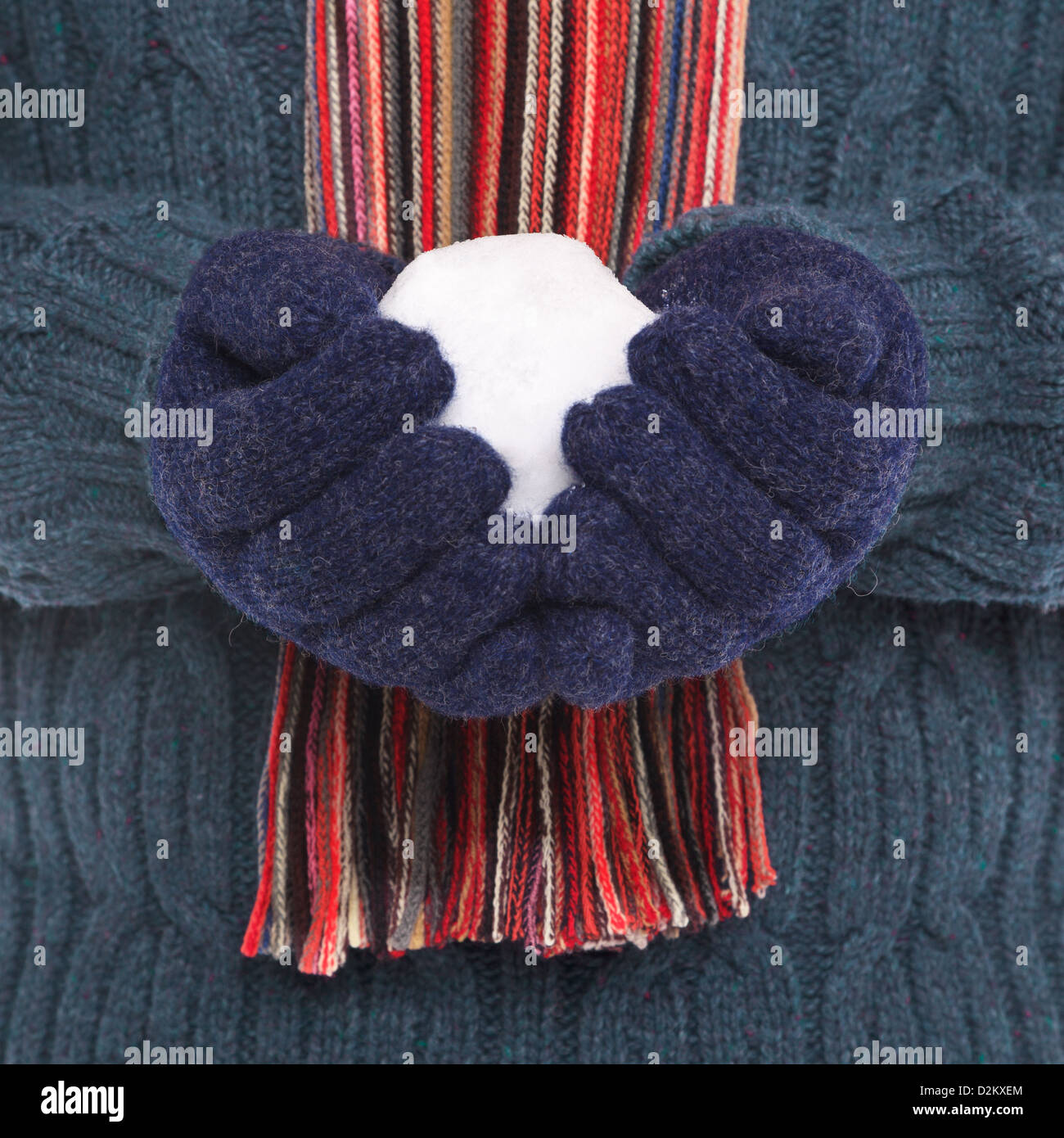 Close up di un uomo che indossa il ponticello di lana, guanti e un foulard tenendo una palla di neve. Foto Stock