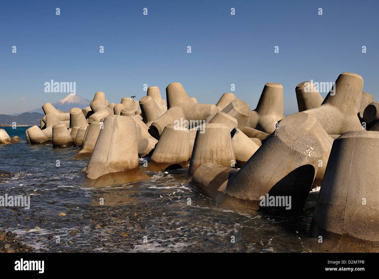 Un lontano il Monte Fuji visto dalla costa vicino a Shimizu, Giappone, con concreete sea-difesa o reef artificiale. Foto Stock