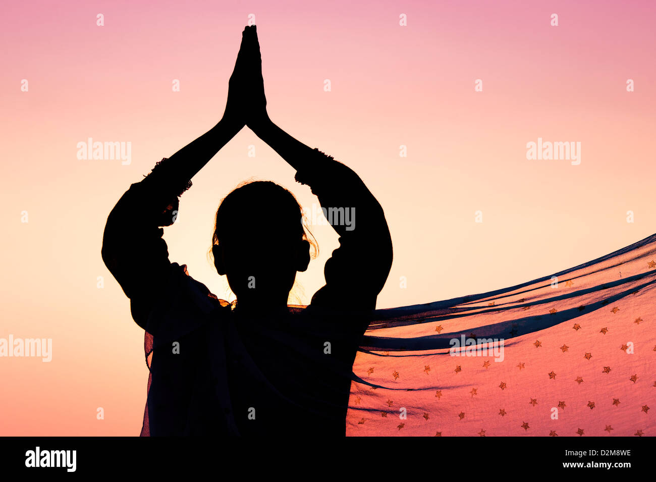 Indian ragazza adolescente pregando al tramonto indossa un velo di stelle. Silhouette. India Foto Stock