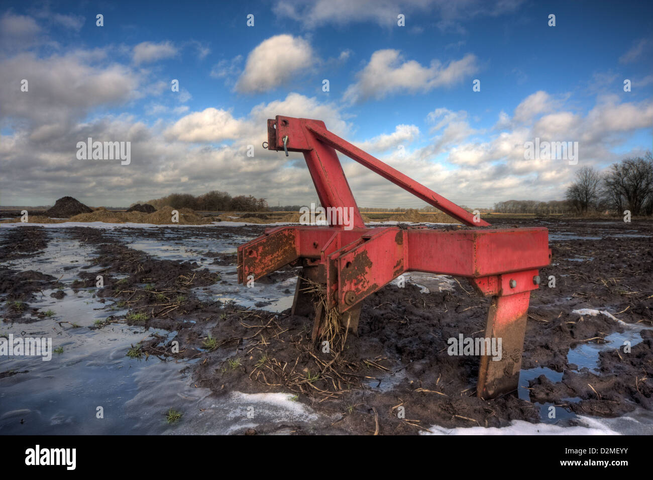 Red harrow, lasciato su un campo fangoso in inverno Foto Stock