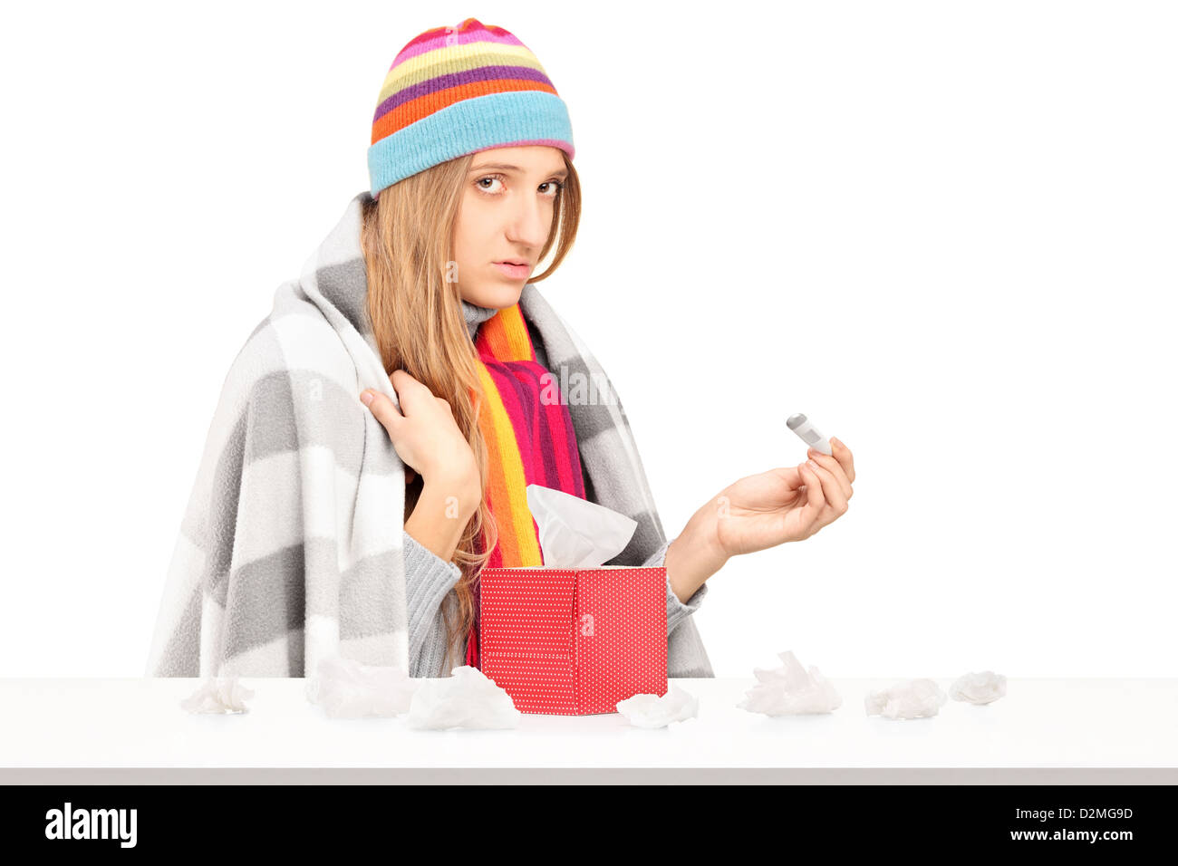 Giovane donna con aviaria tenendo un termometro, box con fazzoletti di carta su un tavolo isolato su sfondo bianco Foto Stock