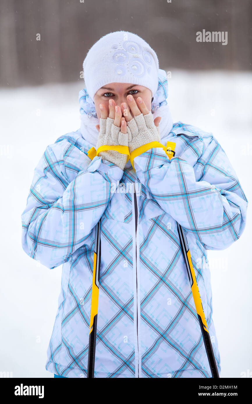 Giovane donna caucasica warming dita con bastoncini da sci in mani. Inverno Sciare Foto Stock