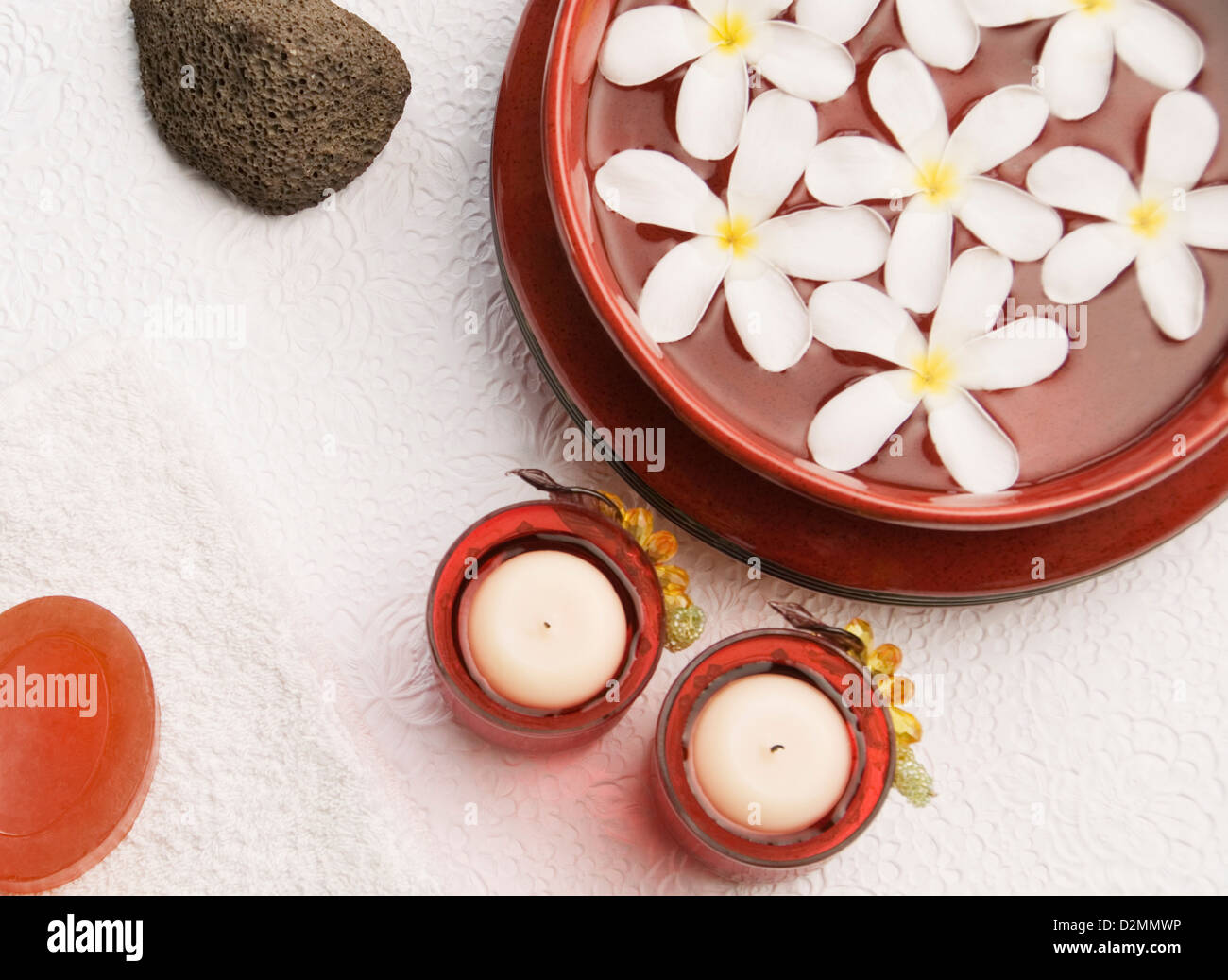 Candele con fiori di frangipani in una ciotola Foto Stock