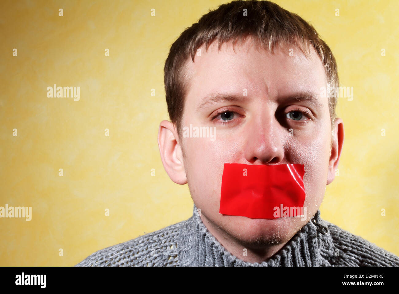 L uomo si chiude la sua bocca il nastro rosso, creativo, che simboleggia la lotta per la libertà di espressione e contro la censura Foto Stock