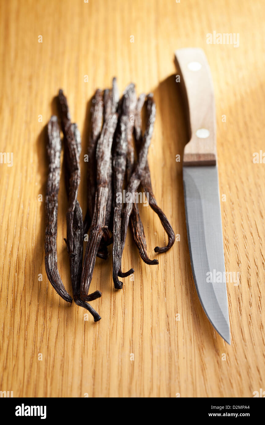 Baccelli di vaniglia con un coltello sul tavolo di legno Foto Stock