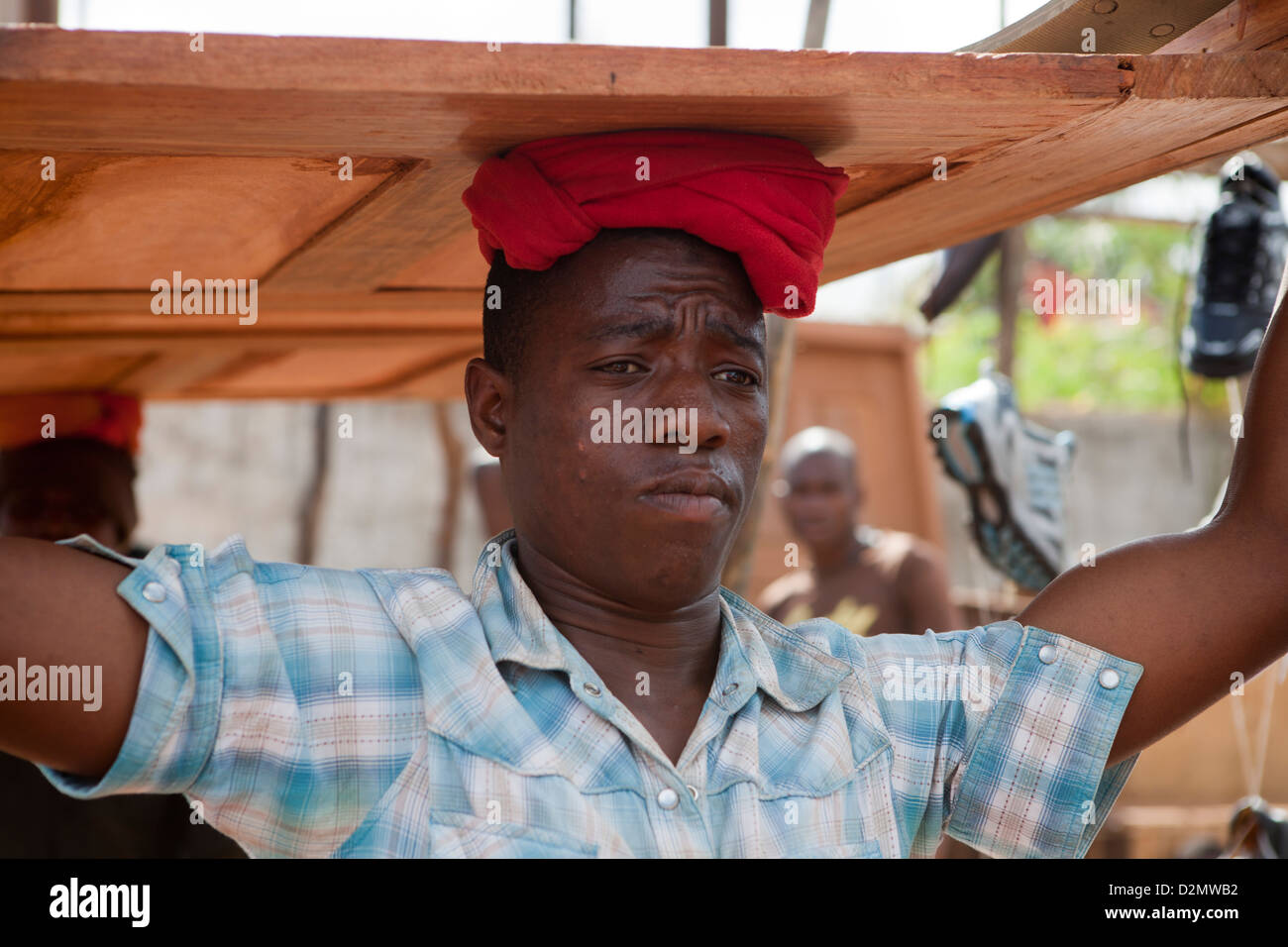 NAMPULA, Mozambico, Maggio 2010 : MERCATO DI DOMENICA - un titolare di stallo effettua una porta di legno che ha appena venduto. Foto Stock