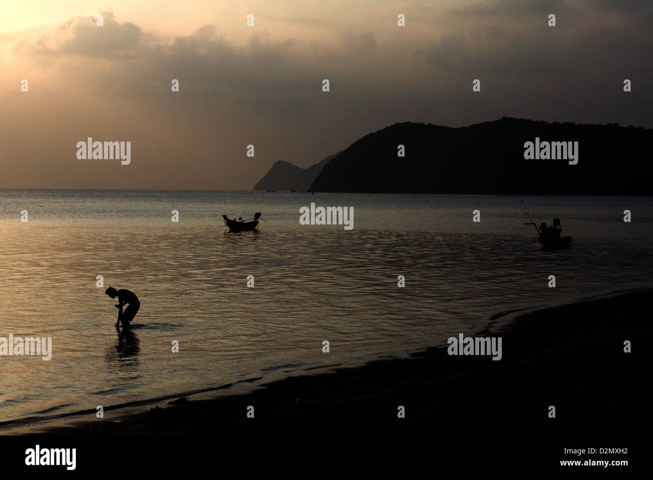 Un uomo stagliano contro il sole al tramonto sulla spiaggia di Thong Sala , Koh Phangan , della Thailandia Foto Stock