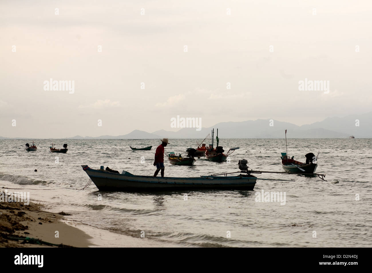 Un uomo si prepara la sua piccola barca da pesca a Thong Sala spiaggia , Thong Sala , Kho Phangan , della Thailandia Foto Stock