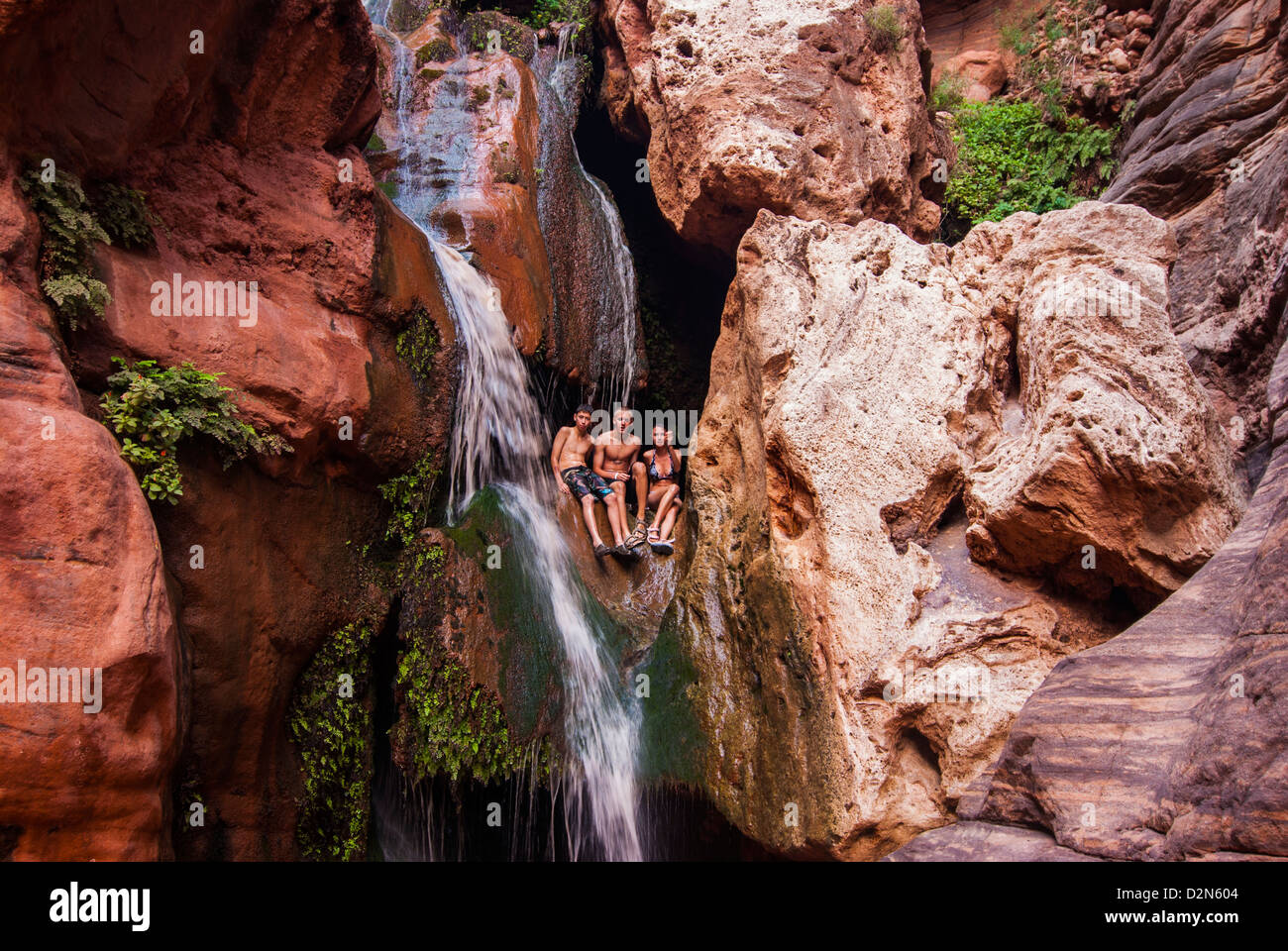 I turisti di balneazione in una cascata, visto mentre il rafting lungo il Fiume Colorado e il Grand Canyon, Arizona, Stati Uniti d'America Foto Stock