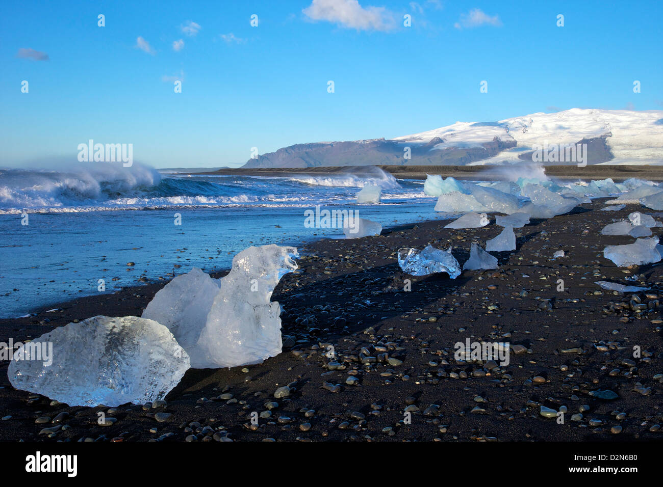 Iceberg sulla sabbia vulcanica spiaggia presso Jokulsarlon con neve sul massiccio del icecap Vatnajokull dietro, Islanda, regioni polari Foto Stock