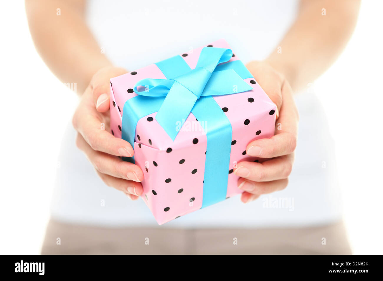Primo piano della donna di mani dono pink polka dot paper legate con un nastro di color turchese come auguri di Natale Foto Stock