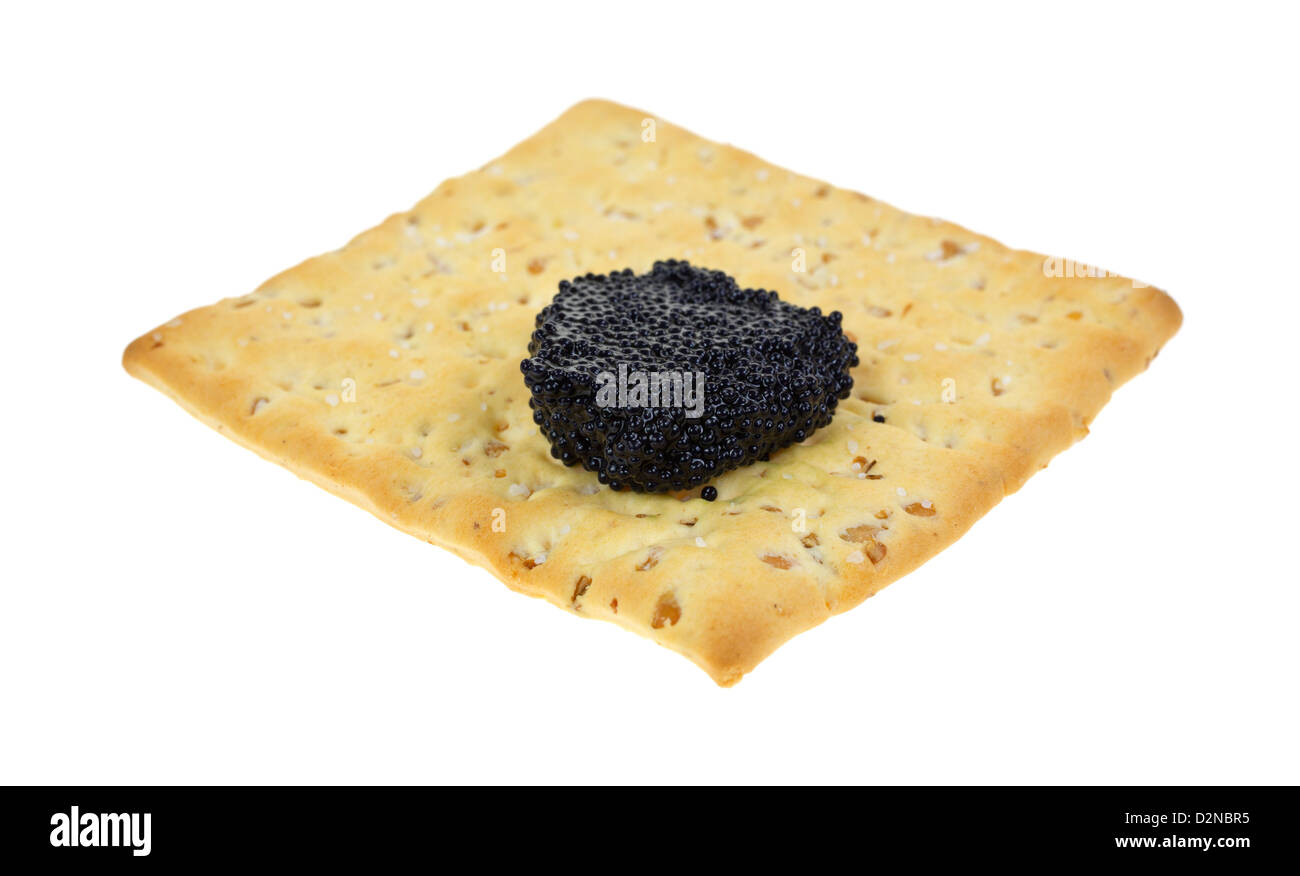 Una massa di pietra del cracker di grano con una piccola porzione di caviale nero su uno sfondo bianco. Foto Stock