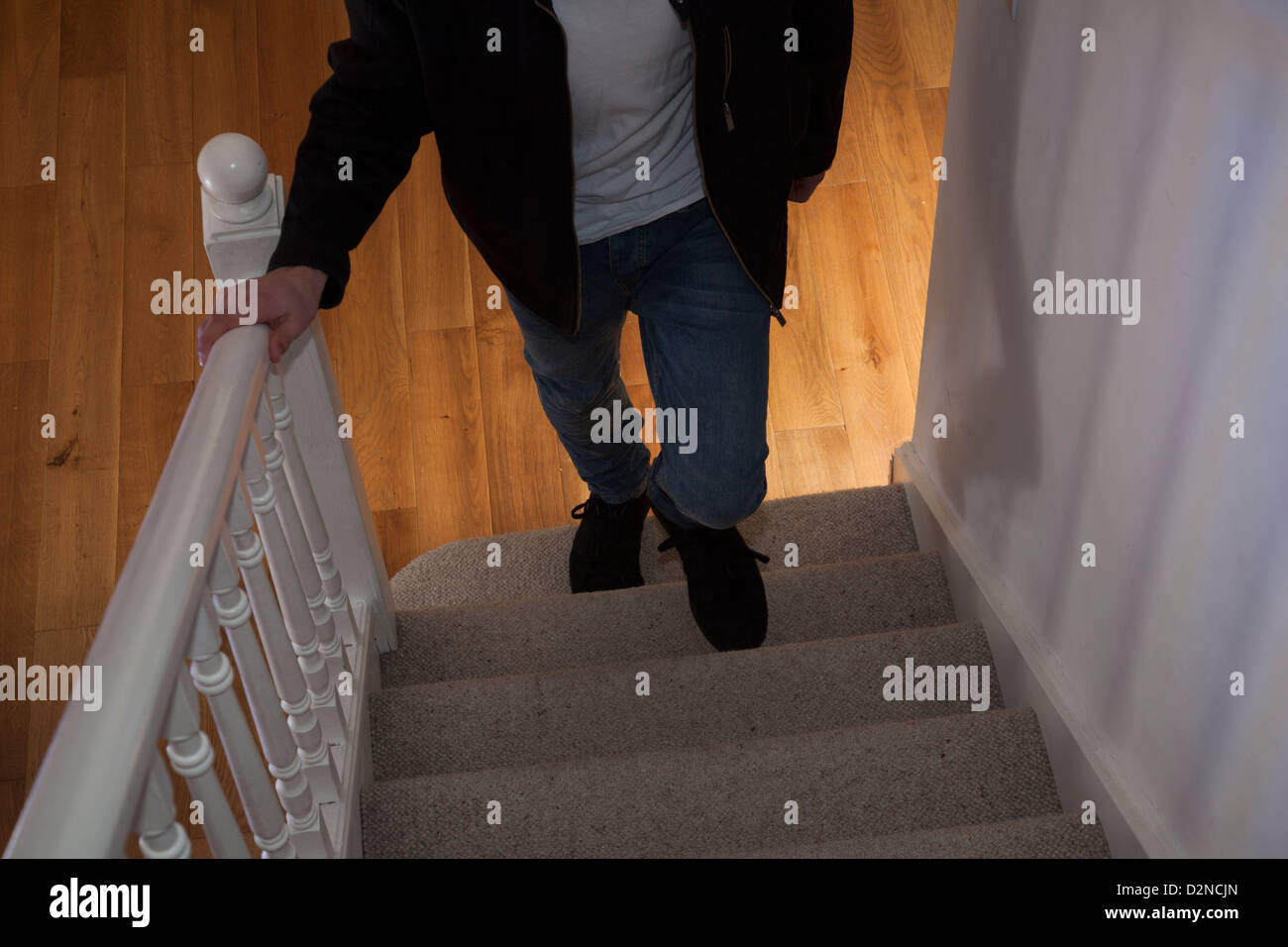 Giovane maschio che indossa jeans e una giacca nera e un teeshirt camminare da solo al piano di sopra la faccia (non mostrato). Foto Stock