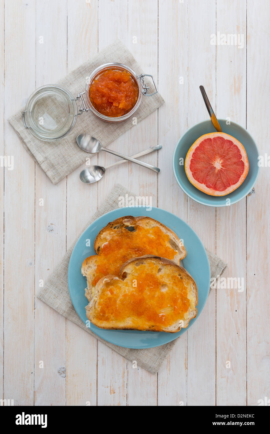 Pompelmo rosa marmellata sul pane tostato, con una mezza pompelmo rosa. Foto Stock