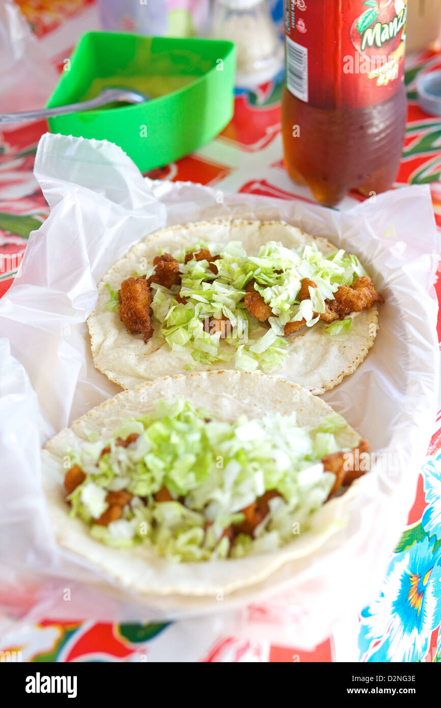Tacos di pesce appena sfornato con lattuga grattugiata, serviti su una tovaglia colorata a Mazatlán, Sinaloa, Messico Foto Stock