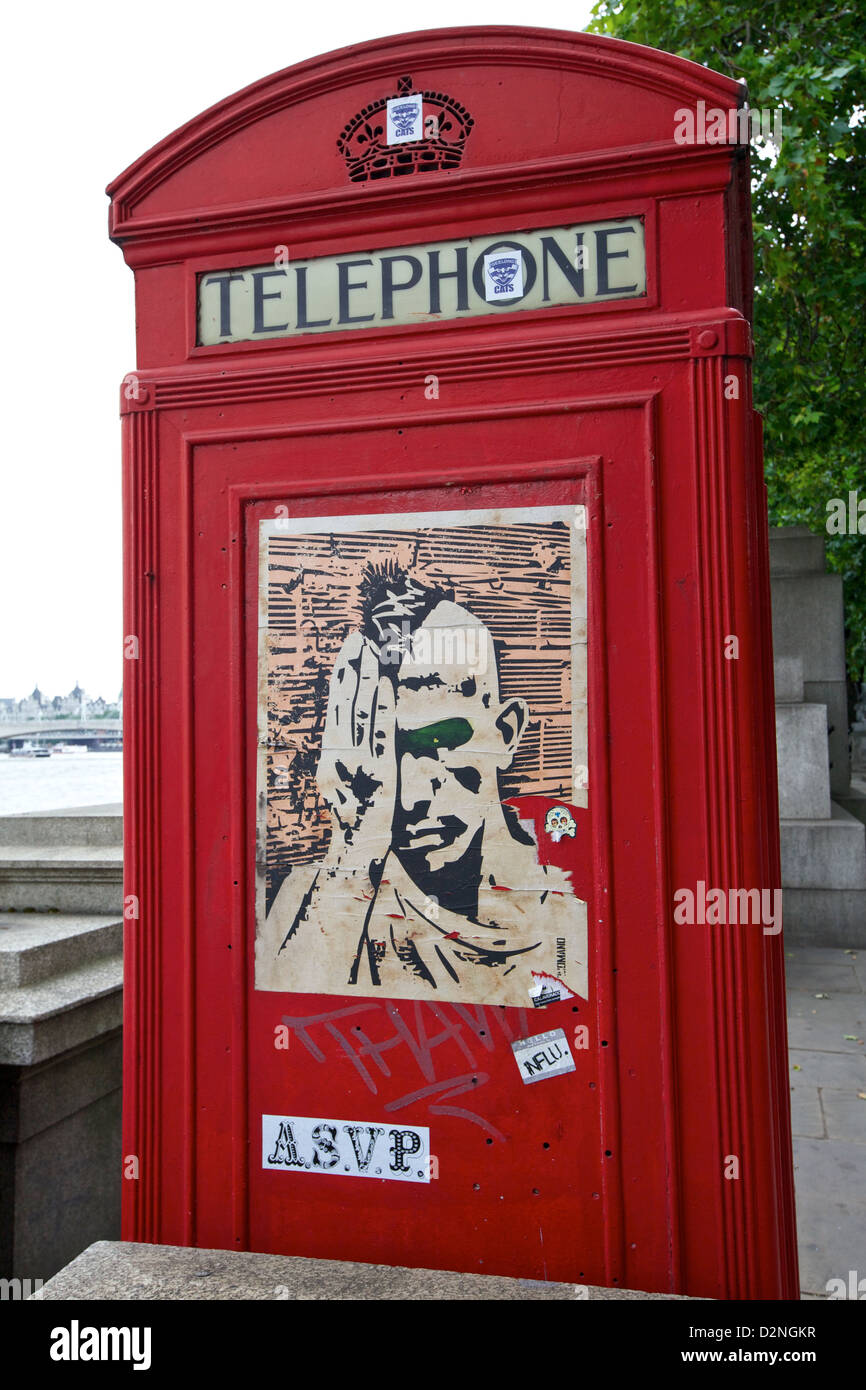 Una classica cabina telefonica rossa a Londra adornata da vibrante Street art, che mescola tradizione con la moderna cultura urbana Foto Stock