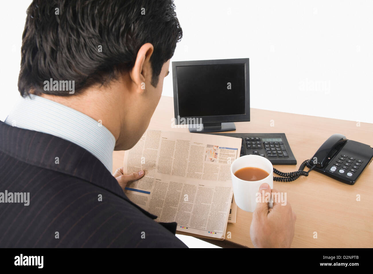 Imprenditore leggendo un giornale e tenendo una tazza di tè Foto Stock